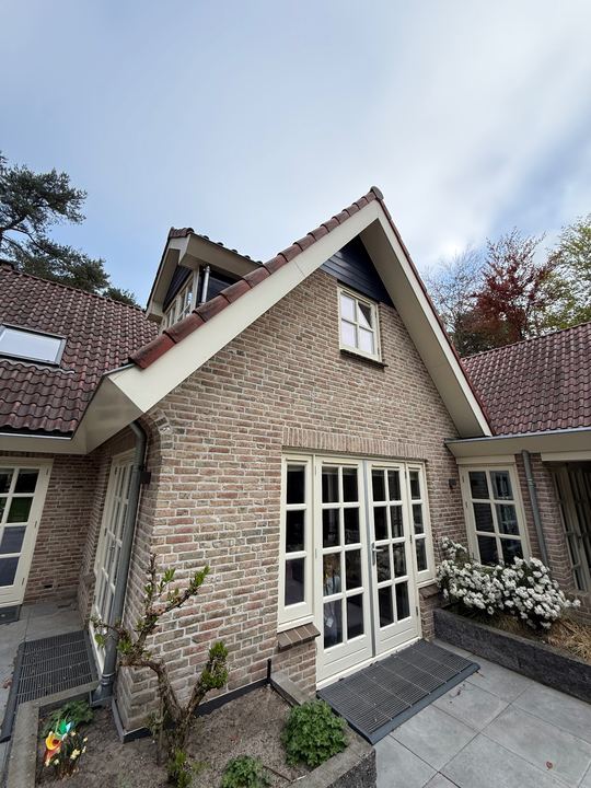 Bakstenen gevel met witte glazen deuren en ramen
